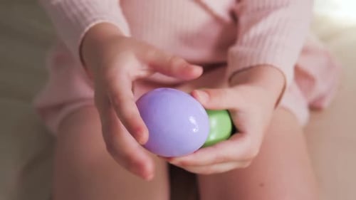 Purple and Green Egg in the Hands of a Child