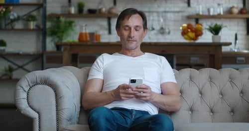 Man sitting on couch using mobile phone
