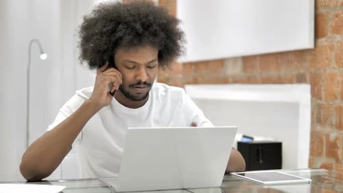 Professional Talking on Cell Phone with Laptop