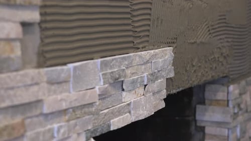 Male Worker Hands Using a Carpenters Level While Setting Stacked Stone Tiles