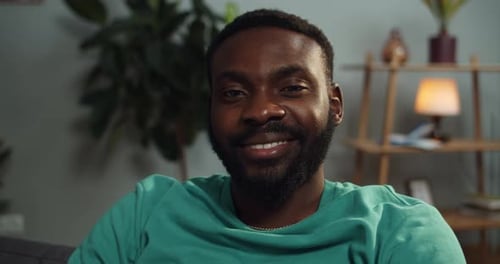 Portrait of Young Afro American Guy Sitting on Sofa and Smiling . Close Up View of Handsome Man