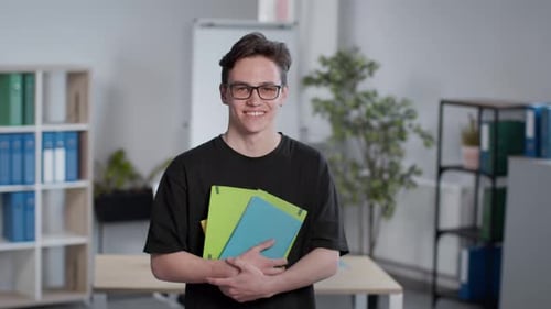 Smiling Young Man Holding Folders in Office