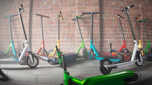 Countless colourful electric scooters left on a sidewalk by a brick wall. 4kHD