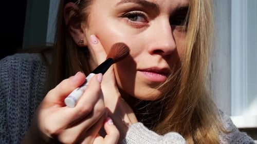 Woman Applies Makeup With Brush in Harsh Sunlight