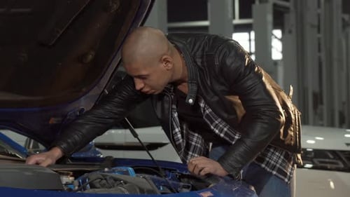 Young African Man Examining Engine of His Car at the Garage
