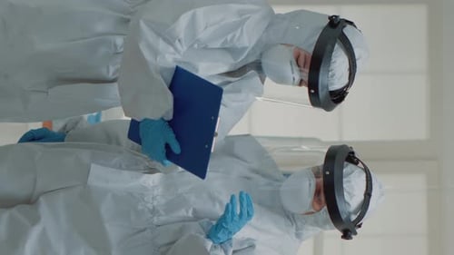 Adults in PPE Suits Holding Clipboard in Vertical Video