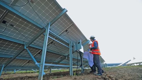Planta de energía solar con dos ingenieros. Dos ingenieros examinan una planta de energía solar