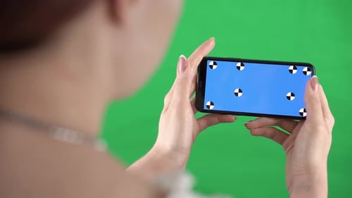 Woman is Zooming Content in Smartphone with Tracking Markers on Display and Green Screen