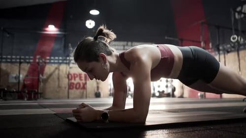 Young female doing planking exercise in gym