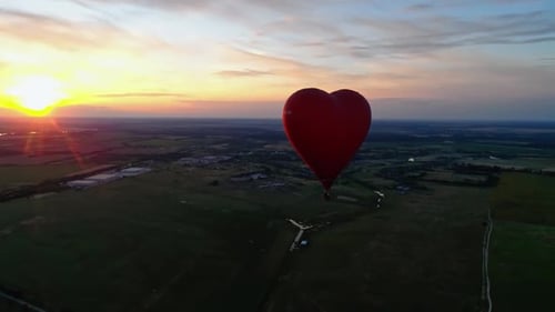 Heart-Shaped Balloon Flying Over Green Fields at Sunrise