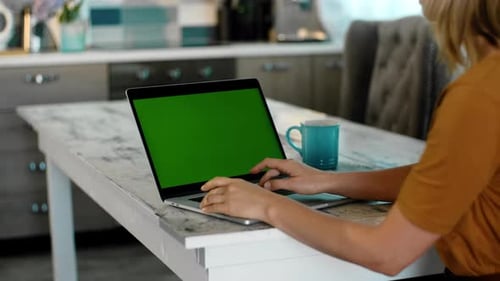 Woman Typing on Laptop with Green Screen at Table
