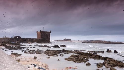 Wide angle camera panning right from a fortified castle building and port of Essaouira, Morocco out