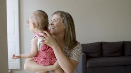 Cheerful Mother Holds Baby in Brightly Lit Home