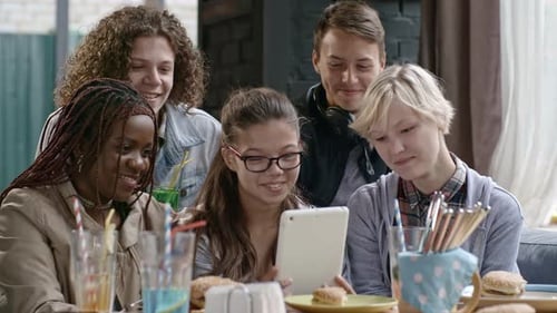 Teen Friends Using Tablet and Laughing in Cafe