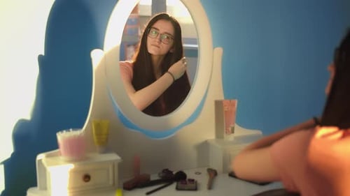 Teen Combs Hair in Vanity Mirror at Home