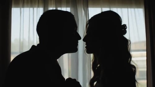 Silhouetted Couple Shares Intimate Moment at Window