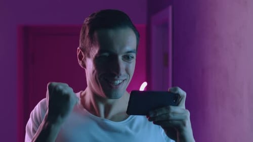 Excited Man Plays Video Game on Mobile Phone