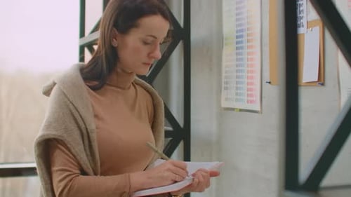 Young Woman Colorist Designer Picks Up Colors Standing Near the Wall