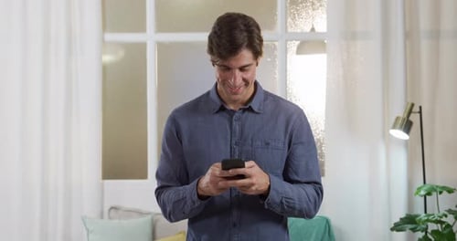 Young Man Smiling While Using Smartphone