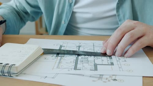 Closeup of Male Hands Measuring Building Plan with Ruler While Architect is Working with Blueprint