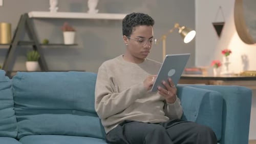 Young Adult Using Tablet on Couch Indoors