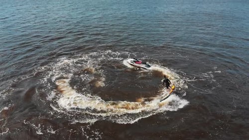 A Man Flying Around Over the Water on the Flyboard in Circles Aerial View
