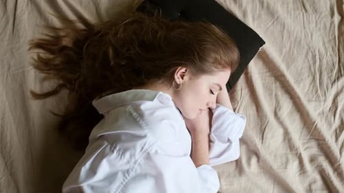 Woman Sleeping Peacefully on a Bed, Top-Down Shot