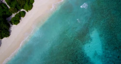 Wide angle fly over abstract shot of a white sandy paradise beach and aqua blue ocean background