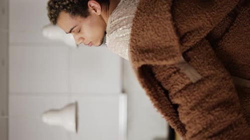 Um homem em um vestido e casaco de pele dançando sensualmente na cozinha close-up
