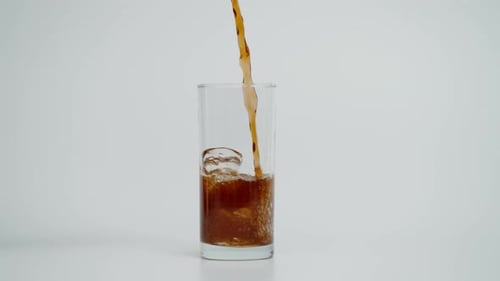 Refreshing Brown Beverage Poured into Glass with Ice