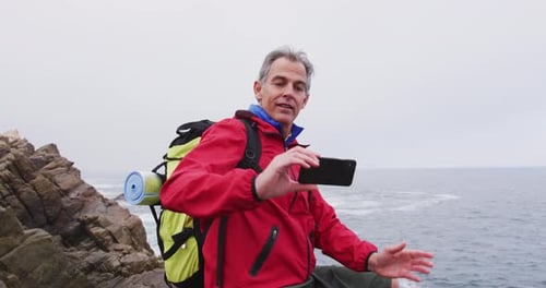 Gray-Haired Man Taking Selfie on Coastal Rocks