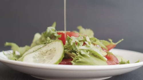 Adding Olive Oil To Fresh Green Vegetable Salad