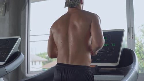 Adult Man Running on Treadmill at the Gym
