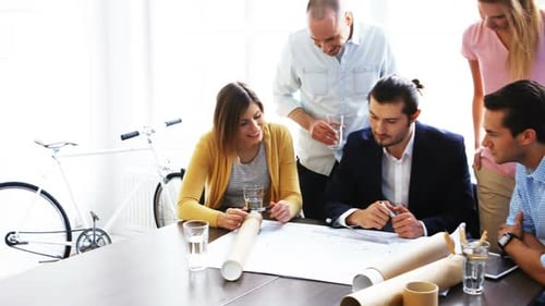 Creative Team Collaborating on Blueprint in Bright Office