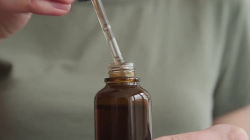 Woman Opens a Brown Medicine Bottle with Dropper