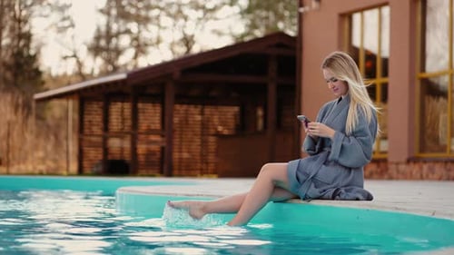 Relaxe no centro de spa termal jovem mulher bonita está descansando perto da piscina aberta balançando as pernas