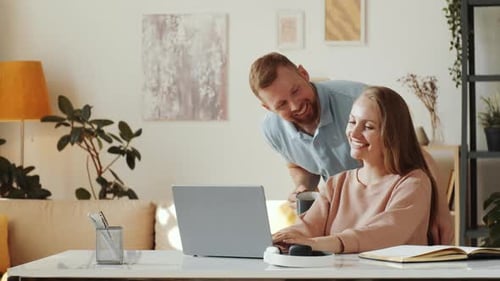 Woman Works On Laptop As Man Brings Coffee
