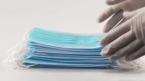 Surgical Masks Stacked and Picked Up by Gloved Hands