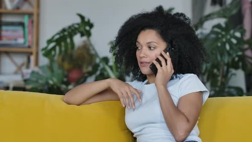 Woman Talking on Cell Phone on Yellow Couch