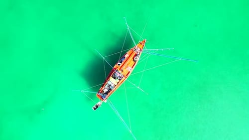 Traditional fishing boat with overhanging nets floating on turquoise sea lagoon near shoreline of tr