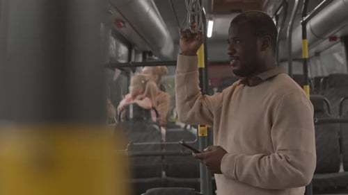 Man Using Phone on Bus During Day