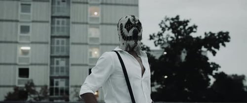 Masked Person Wearing Suspenders in Urban Setting