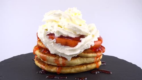 Pfannkuchen mit Erdbeer-Topping und Schlagsahne auf weißem Hintergrund.