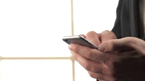 Gros plan sur les mains d'un homme tapant quelque chose sur son smartphone