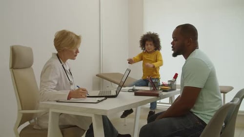 Doctor Consults with Child and Father in Office