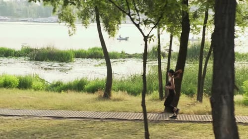 Woman Runs Through Park on Lakeside Path