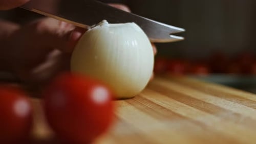 Hands Slicing Onion on Cutting Board with Tomatoes
