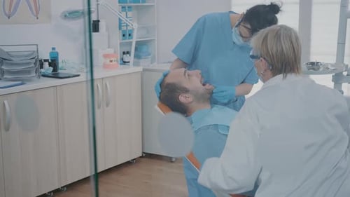 Man Getting Dental Exam by Two Doctors