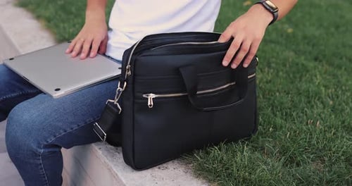 Unrecognizable Man Puts a Laptop Into a Bag