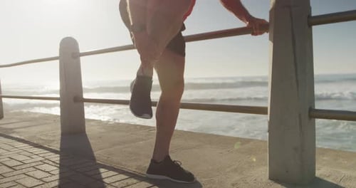 Senior man in pain holding his leg on the promenade